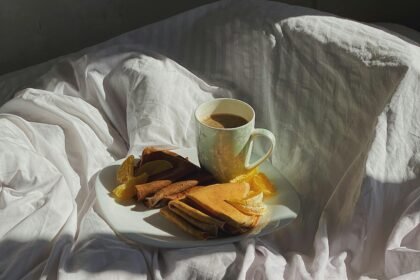 A healthy breakfast in bed with fruit pancakes on white sheets, perfect for people who hate cooking and looking for lazy meal ideas