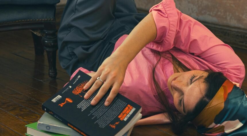 A young woman lying on the floor with her legs up a wall, illustrating the feeling of overthinking and procrastination.