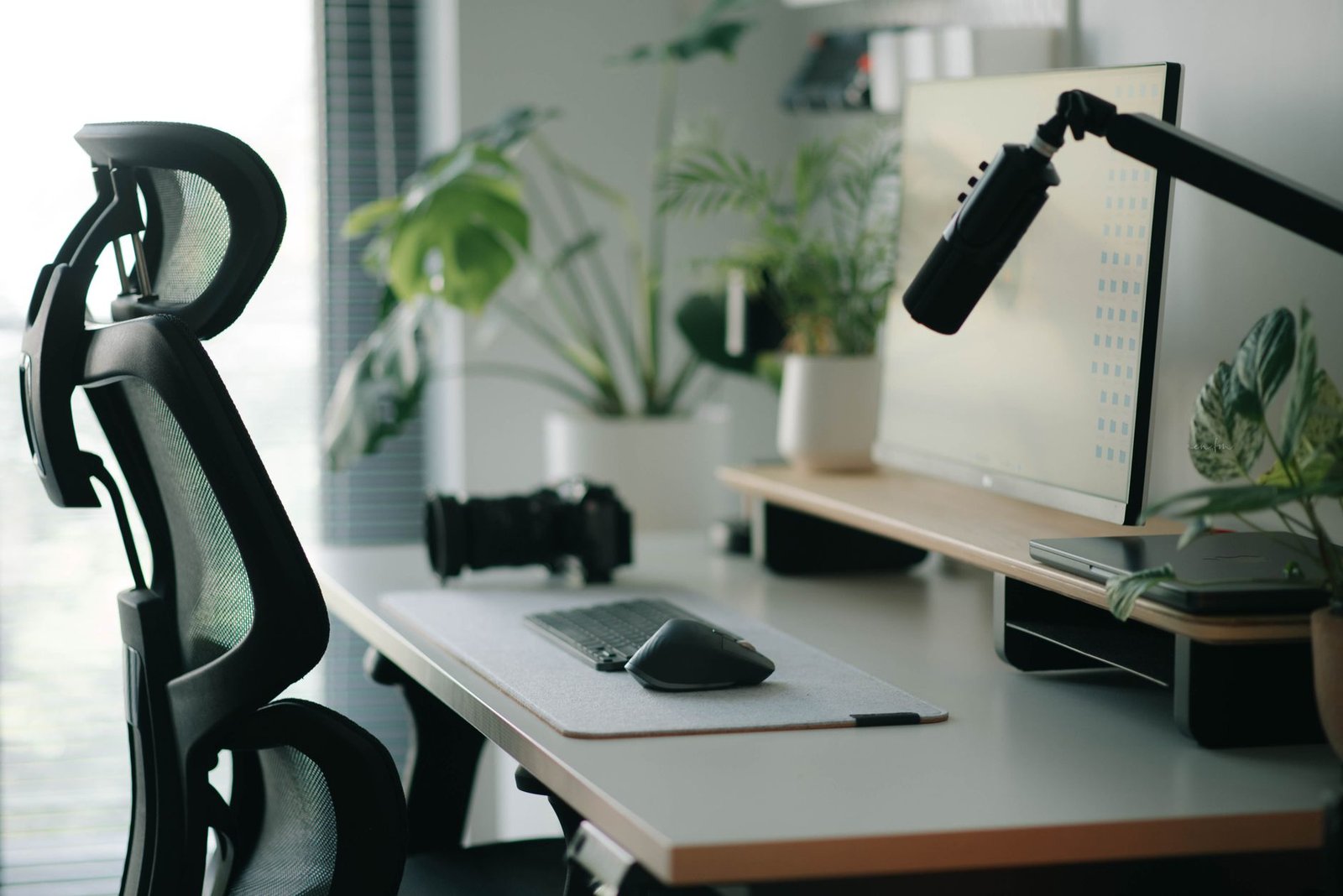 Clean modern desk setup with laptop, monitor, and compact walking treadmill underneath.