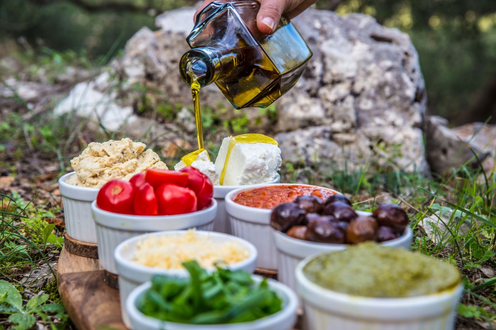 Pouring dark green extra virgin olive oil into a ceramic spoon.