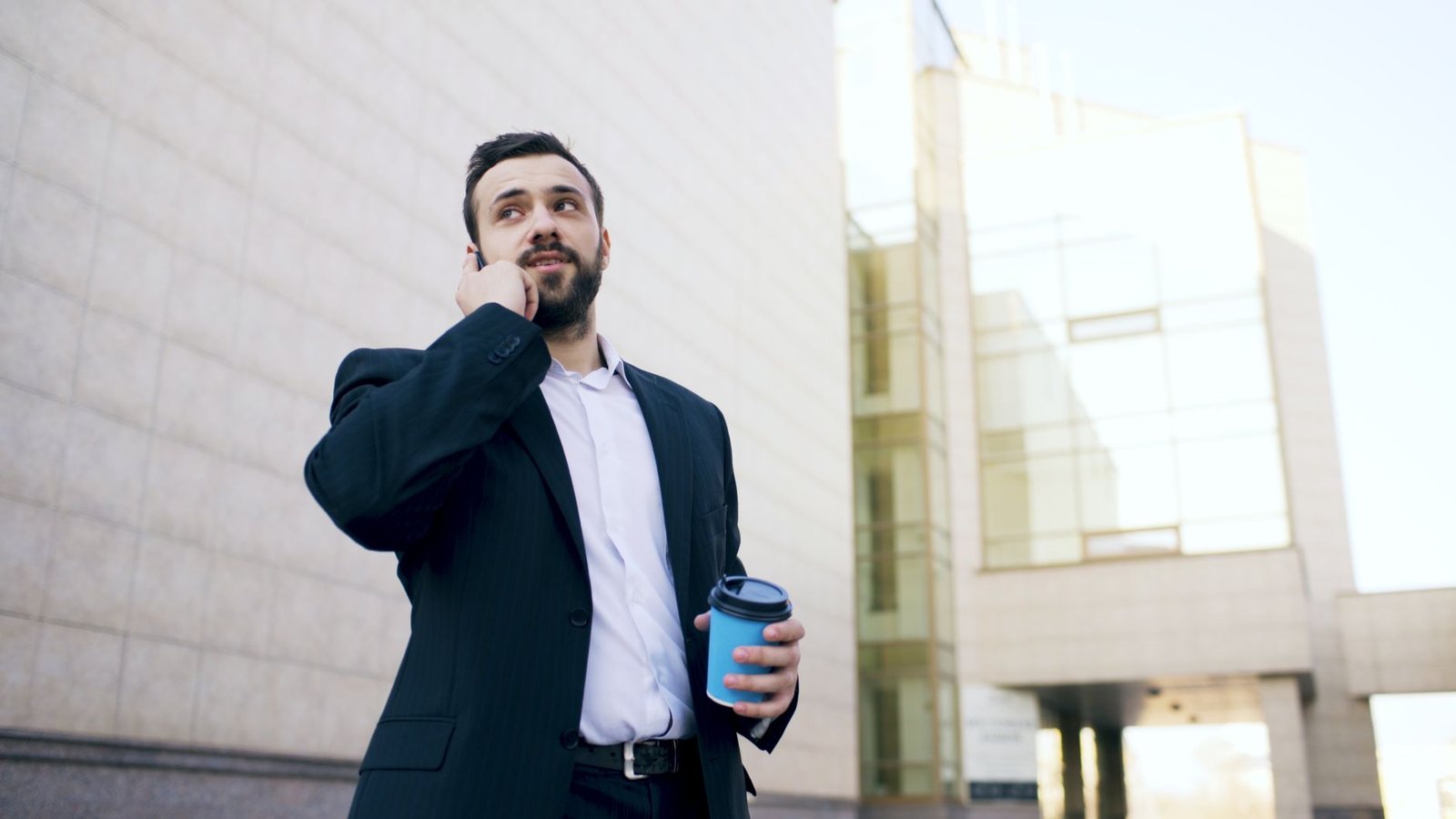 Professional walking and pacing while talking on a smartphone in a modern home office.