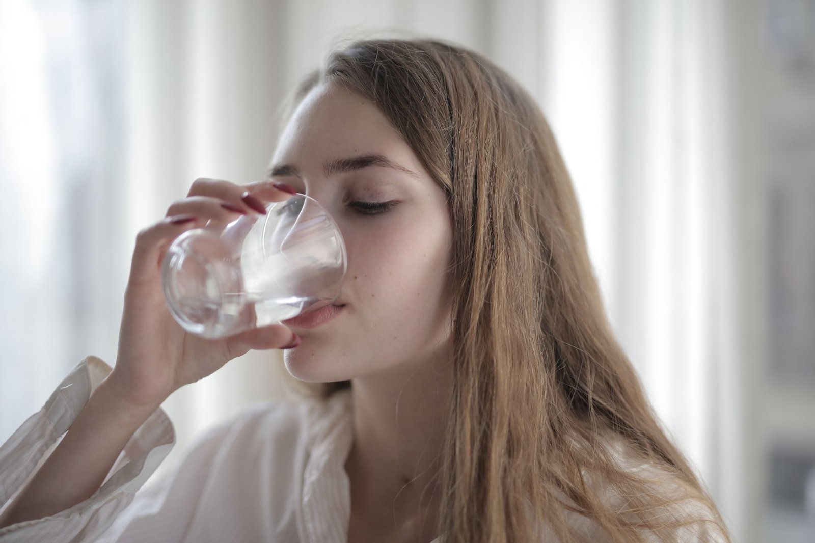 Woman resting with a glass of water after her morning walking pad session.