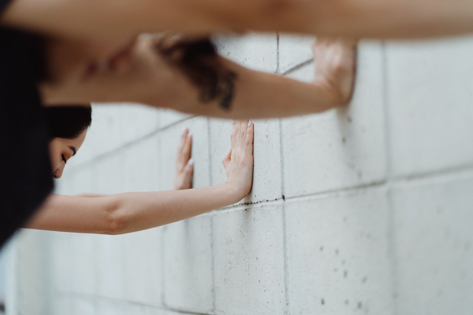 Fitness enthusiast performing wall slides against a white wall for posture.