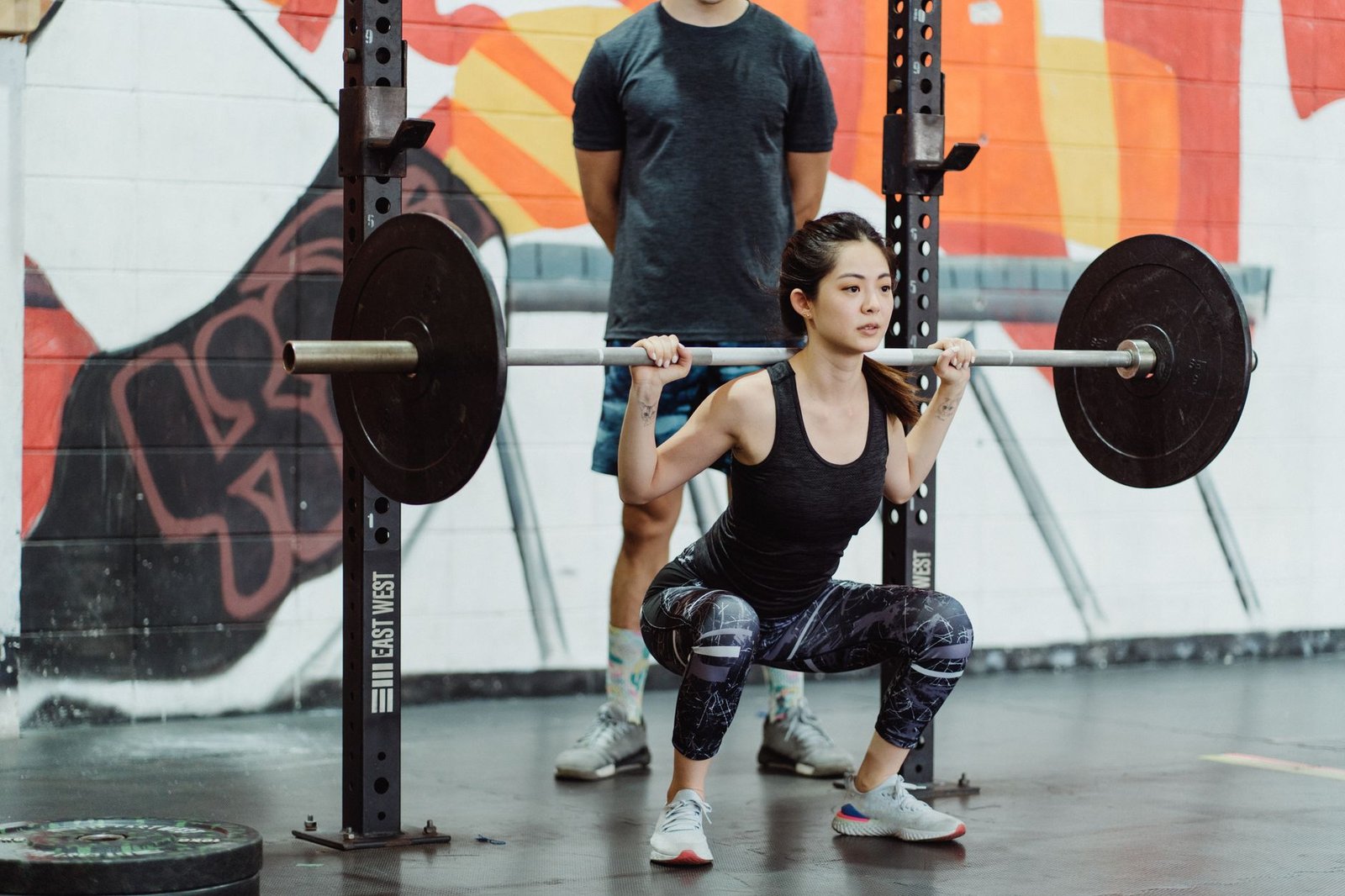 Mature athlete performing heavy barbell back squat in professional strength facility.