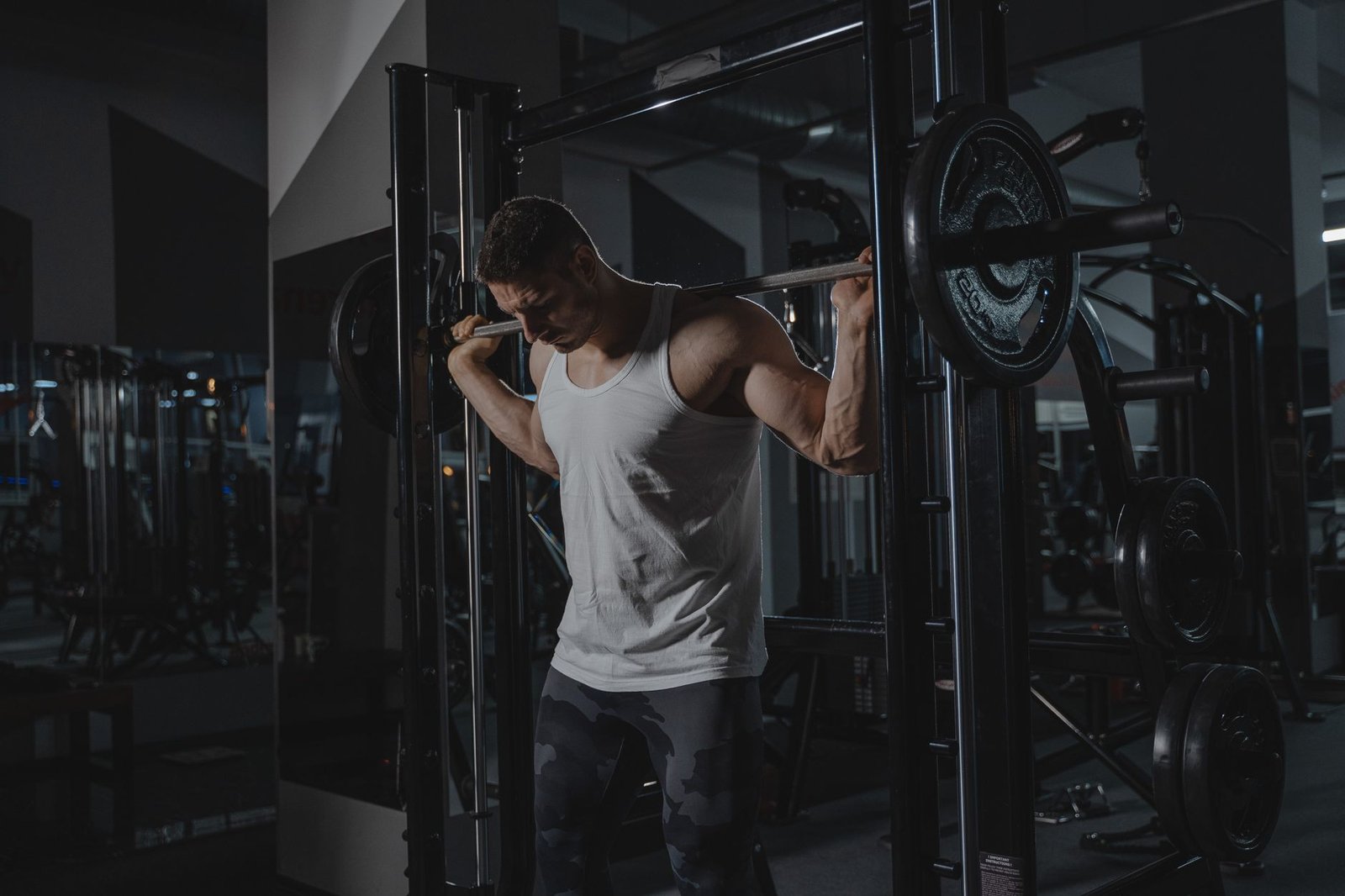 Professional athlete executing a controlled barbell back squat in a gym.