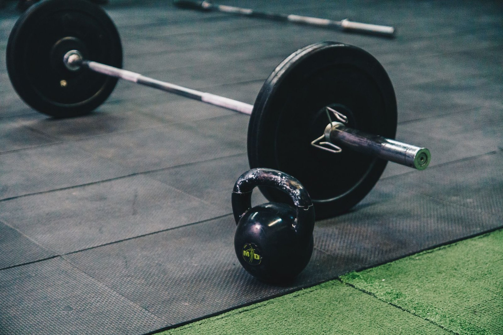 Athlete reviewing real-time velocity metrics on a smartphone attached to a squat rack.