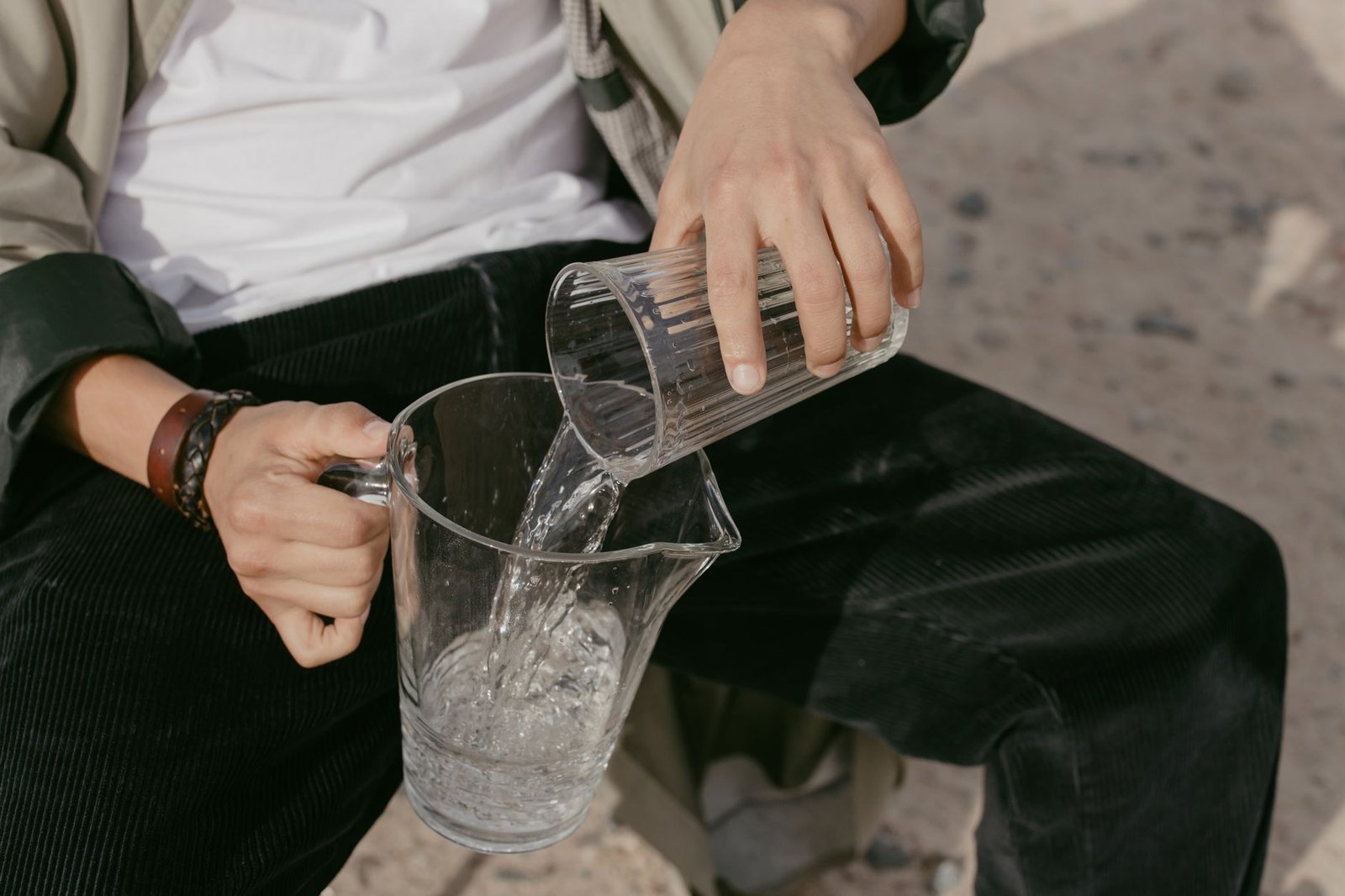 Clear glass pitcher of water with lemon slices on a wooden kitchen island.