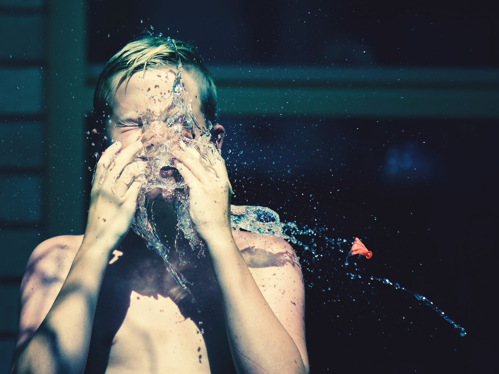 Person splashing cool water on their face in a bright, modern bathroom.