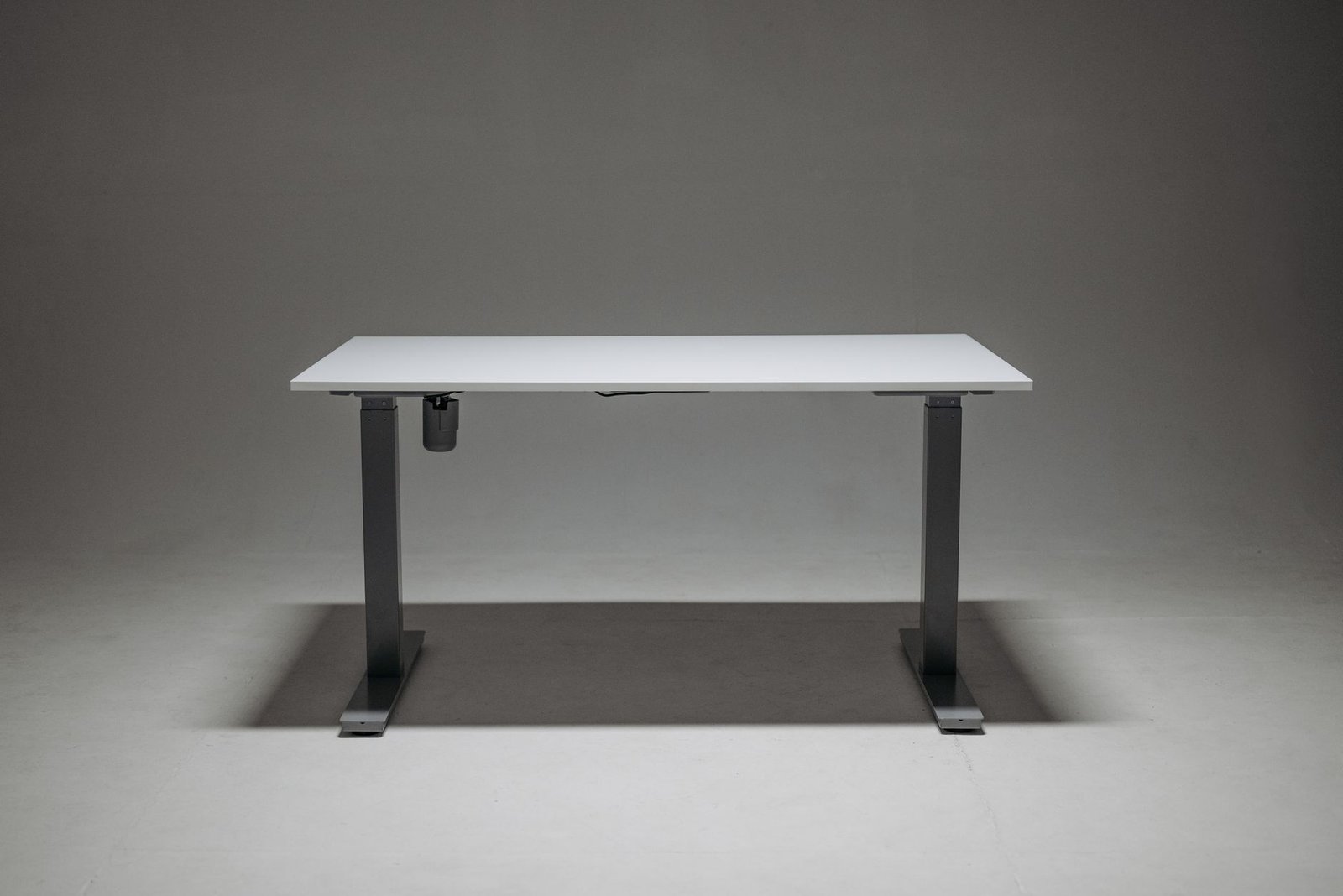 A modern office setup featuring a standing desk and a slim under-desk walking pad.