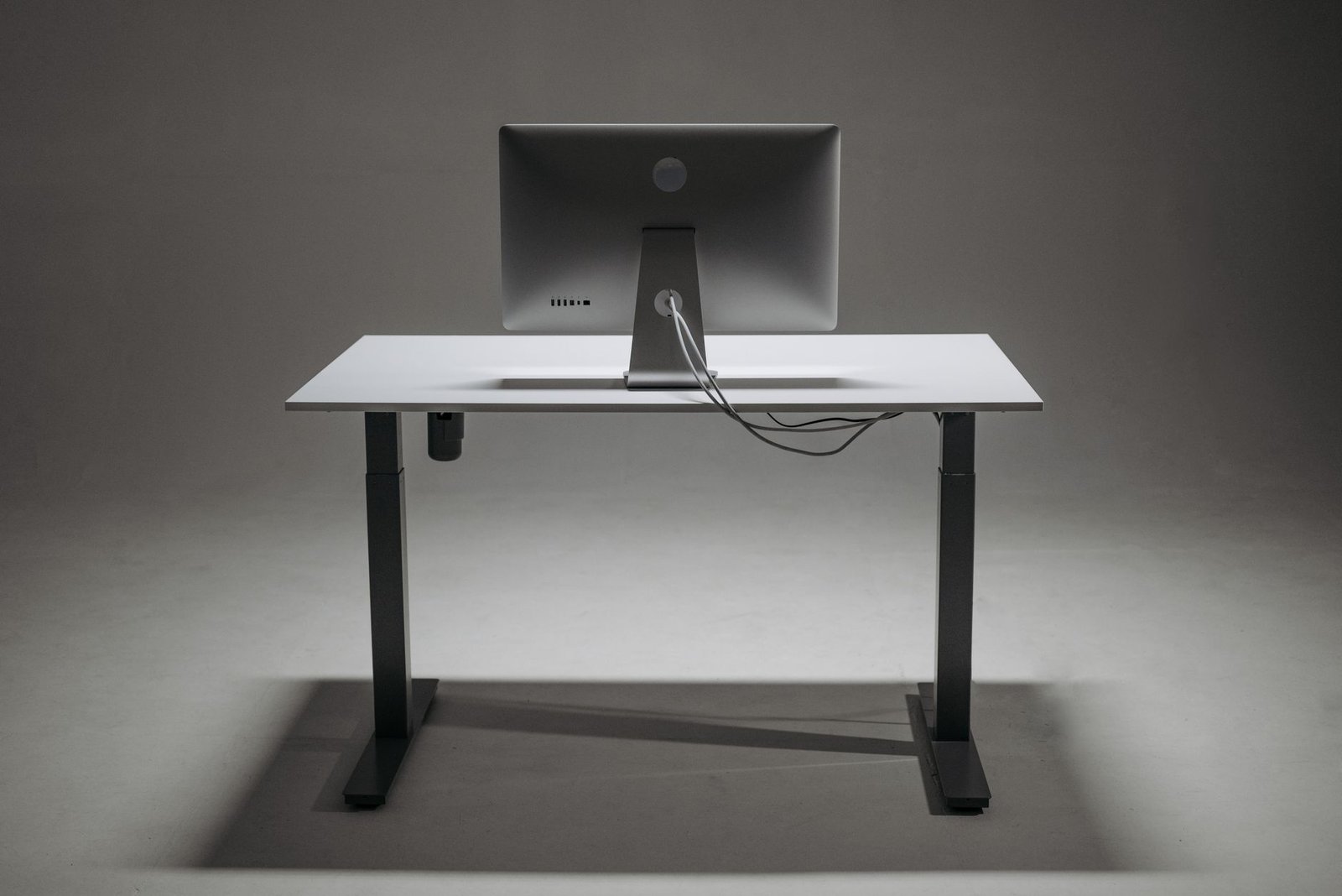 Professional working at a clean sit-stand desk setup with dual monitors.