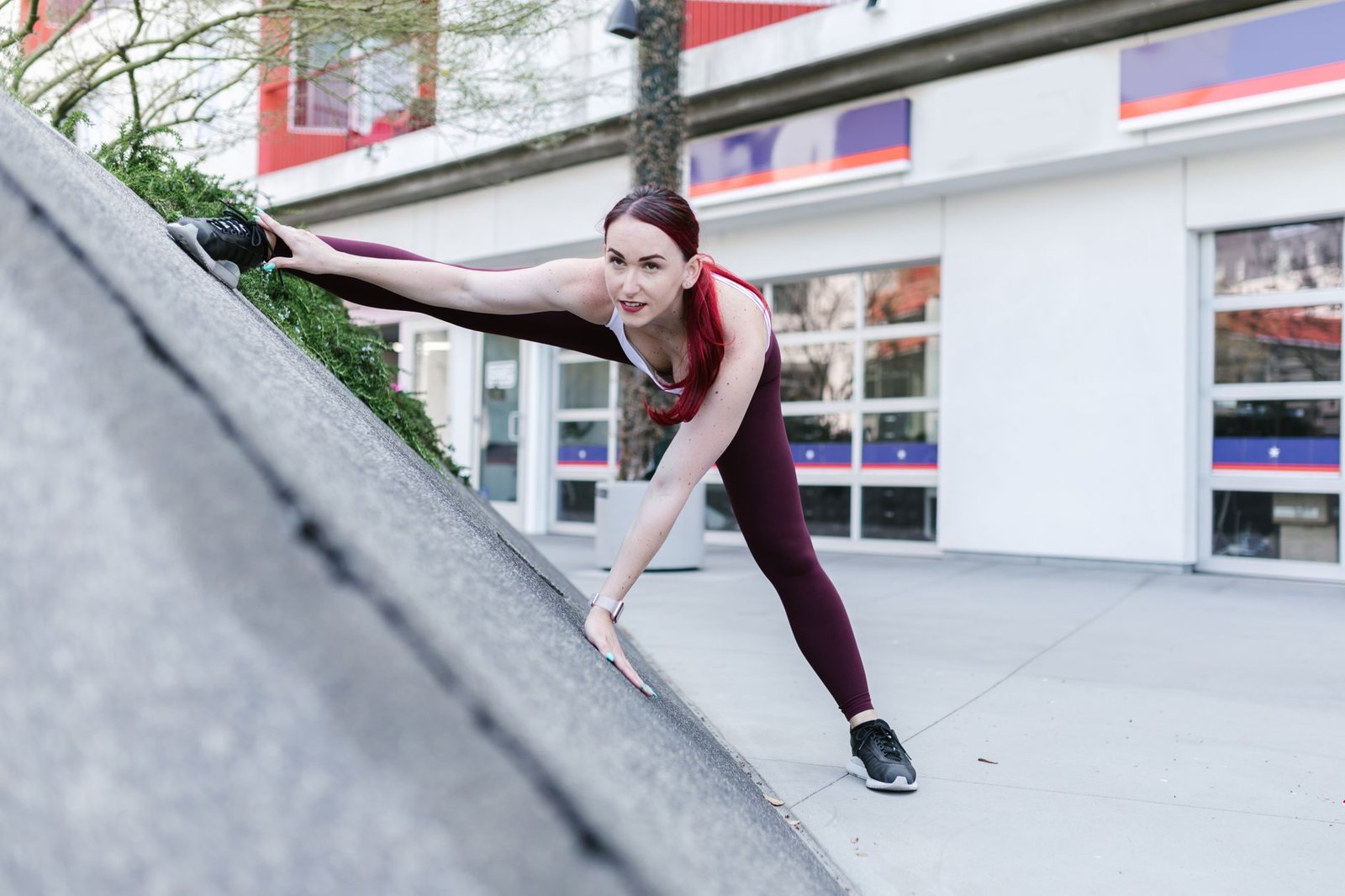 Woman performing a wall stretch for flexibility in a bright room.