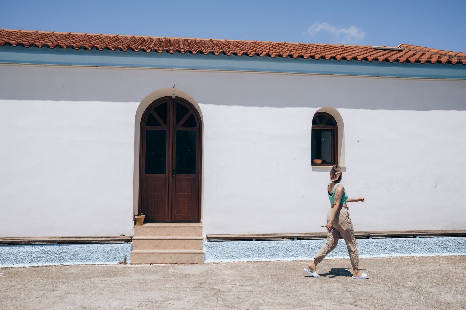 Woman walking on a compact walking pad in a bright living room.